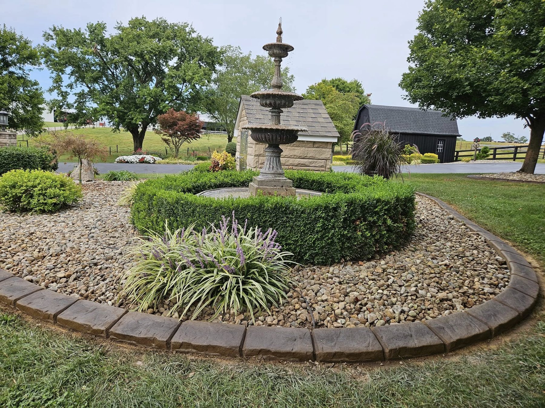 Decorative concrete curbing surrounding a landscaped fountain and river rock garden